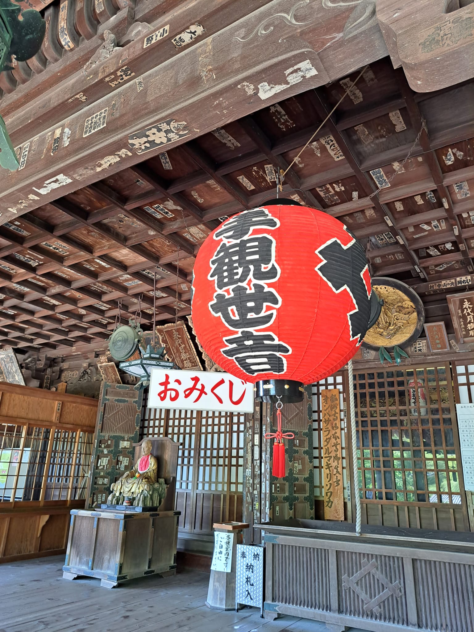 A stunning red lamp with Japanese characters in front of an old wooden Japanese temple, Miidera.