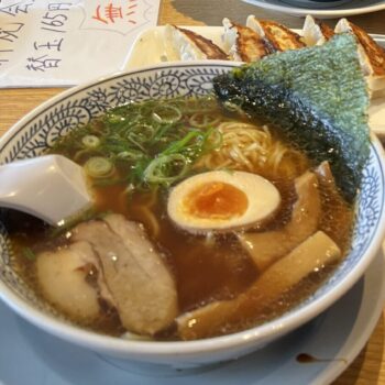 Japanese Ramen with pork and an egg with gyoza dumplings in the background.
