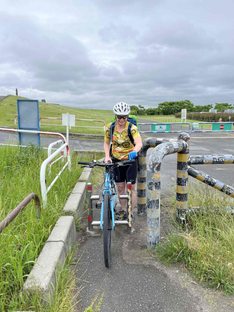 Cyclist walking through bike gates along a cycling path with grey sky in Osaka.
