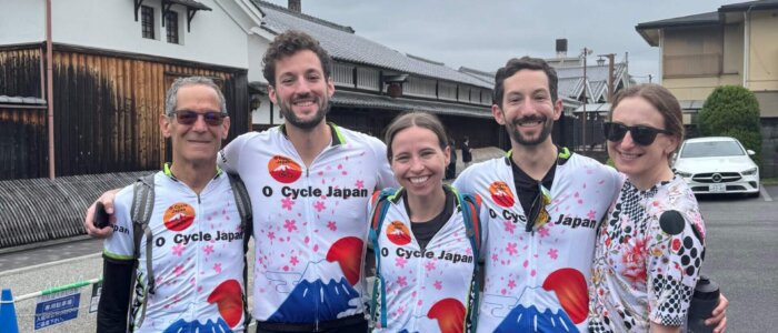 Group of cyclists smiling in front of Gekkeikan sake museum.