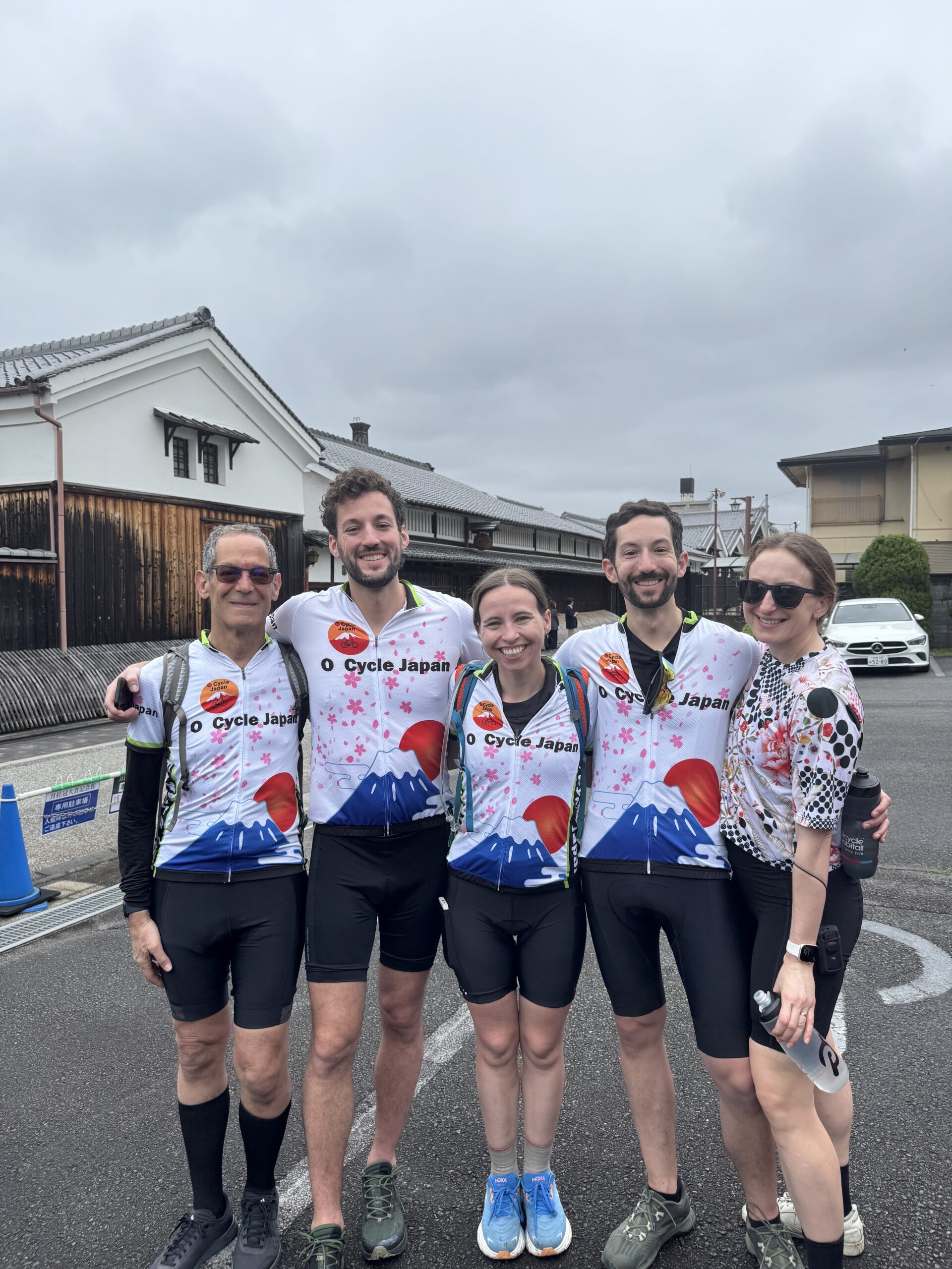Group of cyclists smiling in front of Gekkeikan sake museum.