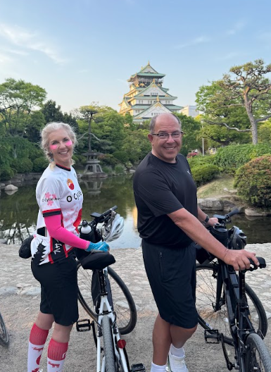 Two cyclists smile as they visit a special spot at Osaka castle.